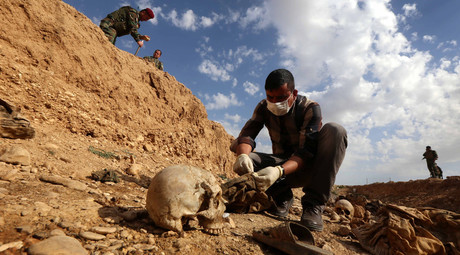 An Iraqi man inspects the remains of members of the Yazidi minority killed by the Islamic State (IS) jihadist group, February 3, 2015. © Safin Hamed
