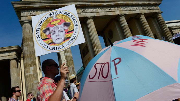 Demonstrators hold up a placard featuring German Chancellor Angela Merkel in front of Berlin's landmark Brandenburg Gate as they take part in a protest against the US National Security Agency (AFP Photo / John Macdougall) 