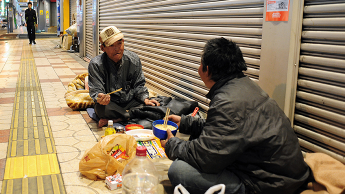 Two homeless men eating a meal outside shuttered shops at night in the western Japanese metropolis of Osaka. (AFP Photo / Richard A. Brooks)