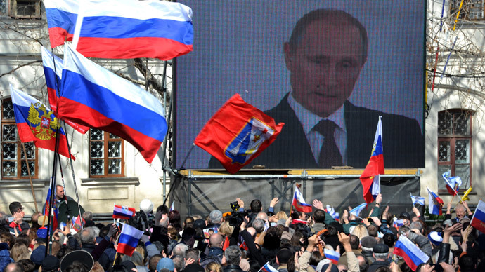 People wave Russian flags as they look at Russian President Vladimir Putin delivering a speech on a screen on March 18, 2014, in Sevastopol. (AFP Photo / Viktor Drachev) 