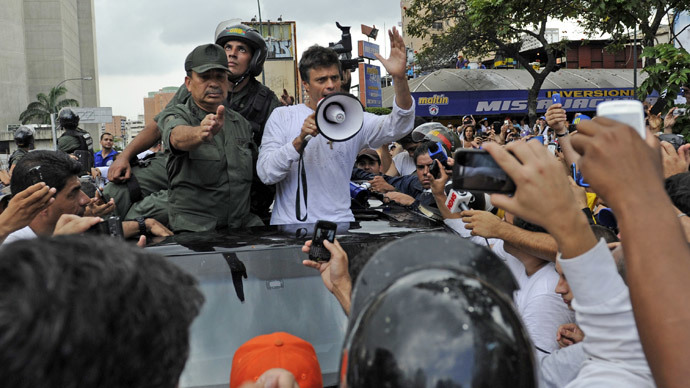 Leopoldo Lopez (C), kiihkeä vastustaja Venezuelan sosialistinen hallitus edessään pidätysmääräyksen jälkeen, kun presidentti Nicolas Maduro määräsi hänet pidätettiin syytettynä murhasta ja väkivaltaan yllyttämisestä, käyttää megafoni rauhoittamaan kannattajia alas jälkeen he estetty tapa National Guard henkilöstö kuljettivat hänet hänen antautua, mielenosoituksen aikana Caracas, 18. helmikuuta 2014.  (AFP Photo / Leo Ramirez)