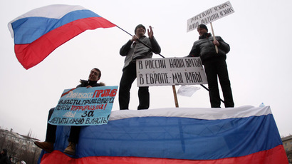 Pro-Russian protesters wave a Russian flag and hold a sign (C) reading "Our brothers are in Russia, we are slaves in Europe" during a rally in front of the regional administration building in the industrial Ukrainian city of Donetsk on March 1, 2014. (AFP Photo)