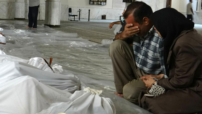 A handout image released by the Syrian opposition's Shaam News Network shows a Syrian couple mourning in front of bodies wrapped in shrouds ahead of funerals following what Syrian rebels claim to be a toxic gas attack by pro-government forces in eastern Ghouta, on the outskirts of Damascus on August 21, 2013. (AFP Photo / Shaam News Network)