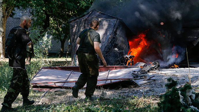 Armed anti-goverment fighters walk in front of garages set ablaze by what locals say was recent shelling by Ukrainian forces in Donetsk August 23, 2014 (Reuters / Maxim Shemetov)