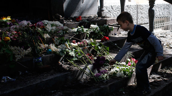 A boy places flowers in front of a gutted police station building in Mariupol, eastern Ukraine May 10, 2014.(Reuters / Marko Djurica)