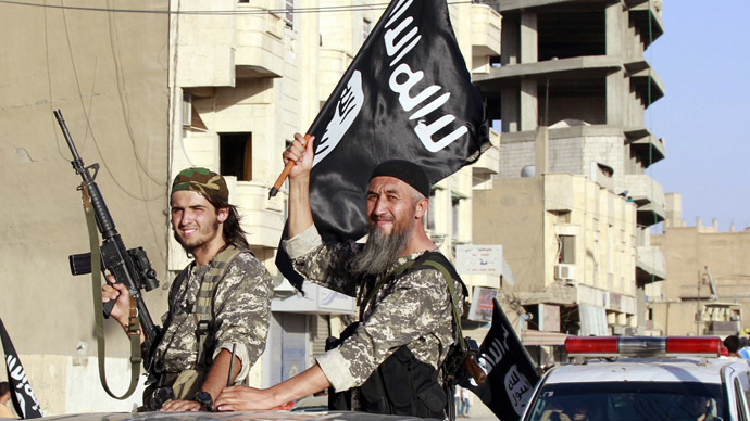 Militant Islamist fighters wave flags as they take part in a military parade along the streets of Syria's northern Raqqa province June 30, 2014. (Reuters)