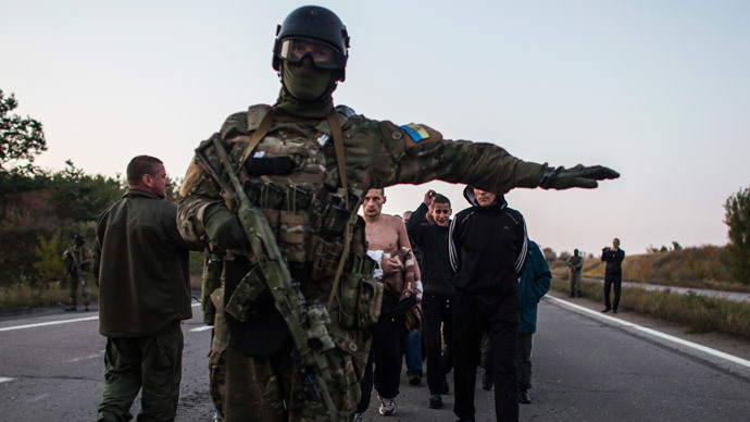A Ukrainian soldier (C) stands guard as rebel captives wait to be exchanged, north of Donetsk, eastern Ukraine, September 28, 2014. (Reuters / Marko Djurica)