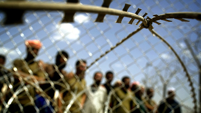 Iraqi detainees stand behind razor wire at Abu Ghraib prison outside Baghdad May 17, 2004. (Reuters)