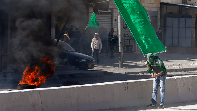 A Palestinian protester holds a Hamas flag during clashes with Israeli troops following a protest against what organizers say are recent visits by Jewish activists to al-Aqsa mosque, at Qalandia checkpoint near the West Bank city of Ramallah November 7, 2014 (Reuters / Ammar Awad)