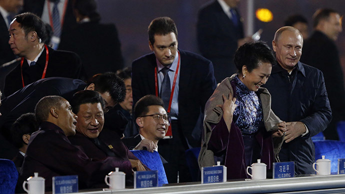 Russia's President Vladimir Putin (R) helps put a blanket on Peng Liyuan (2nd R), wife of China's President Xi Jinping at National Aquatics Center, or Water Cube, in Beijing, November 10, 2014. (Reuters/Stringer)