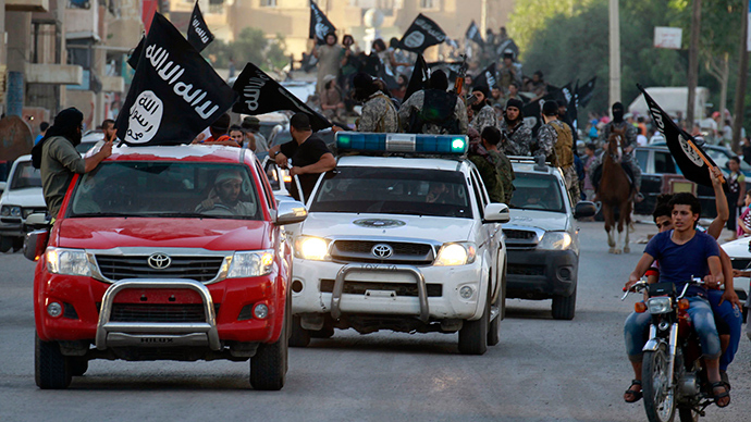 Militant Islamist fighters waving flags, travel in vehicles as they take part in a military parade along the streets of Syria's northern Raqqa province June 30, 2014 (Reuters)