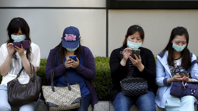 Chinese tourists wearing masks to prevent contracting Middle East Respiratory Syndrome (MERS) use their mobile phones in central Seoul, South Korea June 3, 2015. (Reuters/Kim Hong-Ji)