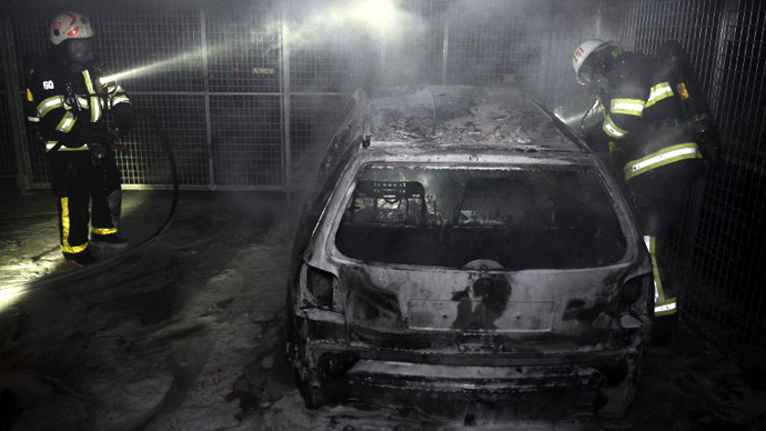 Firemen extinguish a burning car parked in an indoor garage in the Stockholm suburb of Tureberg after youths rioted in several different suburbs for a fourth consecutive night on May 24, 2013. (AFP Photo / Jonathan Nackstrand)