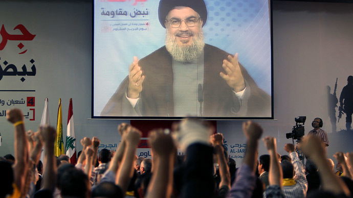 Supporters of Hassan Nasrallah (portrait), the head of Lebanon's militant Shiite Muslim movement Hezbollah raise their fists as they watch him giving a televised address in Beirut (AFP Photo)