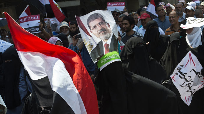 Supporters of the Muslim Brotherhood and ousted Egyptian president Mohamed Morsi hold his picture as they march towards Cairo University to demand his reinstatement in Cairo on July 19, 2013.(AFP Photo / Khaled Desouki)