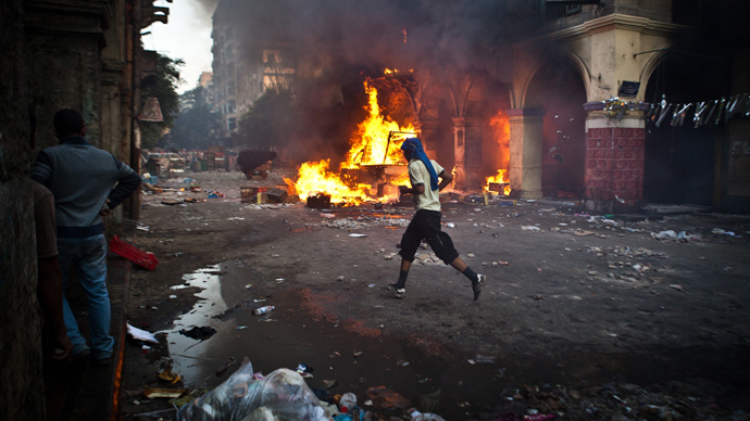 A supporter of the Muslim Brotherhood and of ousted president Mohamed Morsi runs past a burning vehicle during clashes with security officers close to Cairo's Ramses Square, on August 16, 2013 (AFP Photo / Virginie Nguyen Hoang)