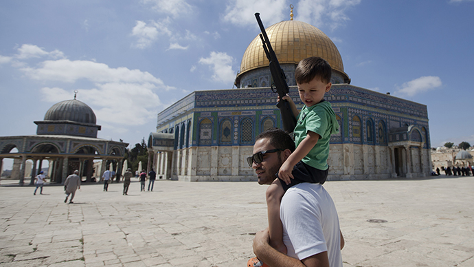 A Palestinian man carries on his shoulders a child holding a fake gun outside the Dome of Rock at the Al-Aqsa Mosque compound, Islam's third most holy site, on September 4, 2013 after disturbances that caused the temporary closure to the access of the Mosque. (AFP Photo / Ahmad Gharabli)