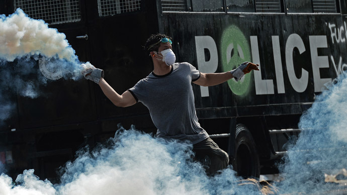 A Thai anti-government protester throws a tear gas canister back to the police during an ongoing rally outside Government House in Bangkok on December 2, 2013. (AFP Photo)