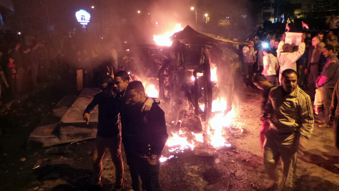 Angry Egyptians set fire to a microbus, said to be belong to a company owned by a businessman who supports the Muslim Brotherhood, after passengers allegedly held up four fingers, the symbol known as "Rabaa", during the funeral of those killed in a car bomb attack earlier in the day, in the Egyptian city of Mansura, North of Cairo, on December 24, 2013.(AFP Photo / Mahmoud Khaled)