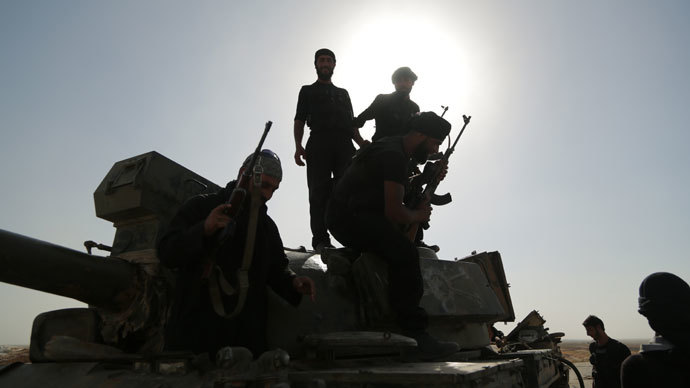 Syrian rebels inspect a tank that was left behind by government forces following clashes in the outskirts of the northern city of Raqqa on July 1, 2013.(AFP Photo / Mezar Matar)