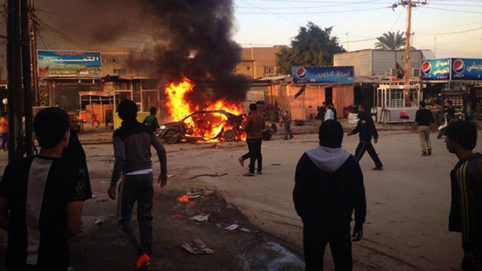 Iraqis gather around a burning car at the scene of an explosion in the Shiite Muslim Al-Amin district of Baghdad on December 8, 2013.(AFP Photo / STR)