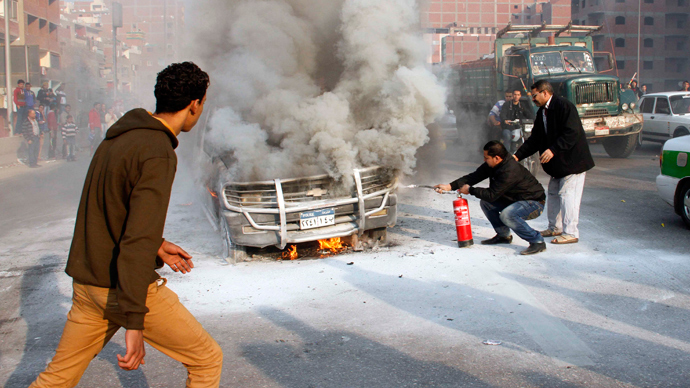 Egyptians try to extinguish a police vehicle set on fire by Muslim Brotherhood supporters on a ring road in the capital, Cairo, on January 3, 2014 as thousands of protesters backing deposed president Mohamed Morsi rallied across the country before police moved in to disperse them, sparking clashes (AFP Photo / Kaled Kamal)