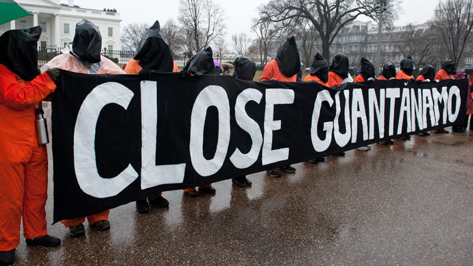 Protestors wear orange detainee jumpsuits and black hoods as they hold a banner calling for the closing of the US detention center at Guantanamo naval base in Cuba in front of the White House in Washington on January 11, 2014 to mark the 12th anniversary of the arrival of the first detainees at the controversial jail. (AFP Photo / Nicholas Kamm)