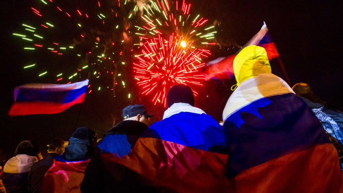 People wrapped with Russian flags watch fireworks during celebrations after the preliminary results of today's referendum are announced on Lenin Square in the Crimean capital of Simferopol March 16, 2014.( Reuters / Thomas Peter)