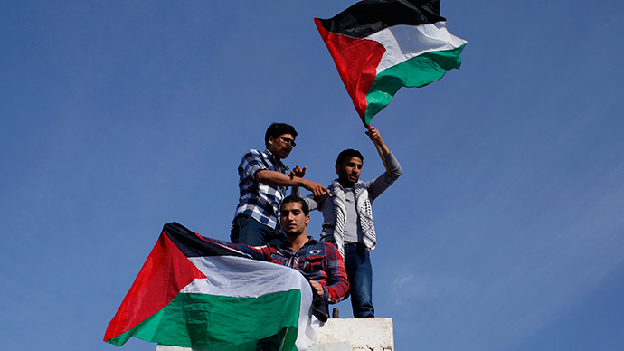Palestinians hold national flags as they celebrate after an announcement of a reconciliation agreement in Gaza City April 23, 2014 (Reuters / Ibraheem Abu Mustafa)