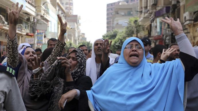 Relatives and families of supporters of ousted President Mohamed Mursi do the Rabaa sign near security forces, after hearing the sentence handed to Muslim Brotherhood leader Mohamed Badie and other Brotherhood supporters, at the court in Minya, south of Cairo April 28, 2014. (Reuters)