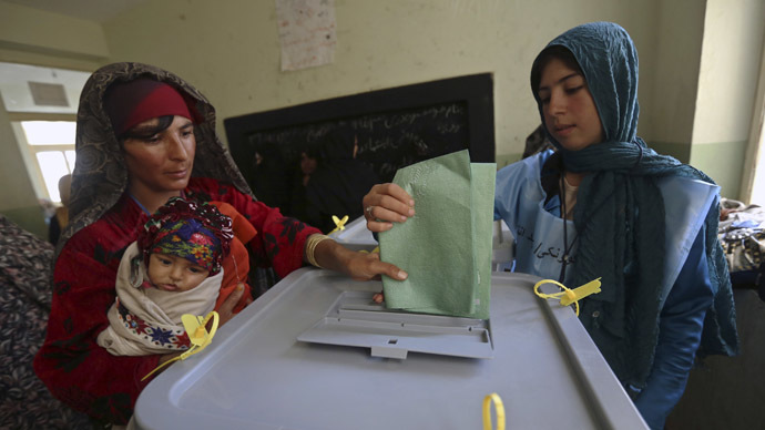 An Afghan woman carrying a child casts her vote at a polling station in Adraskan district, Herat province April 5, 2014. (Reuters/Mohammad Ismail)