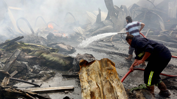 Members of the Libyan emergency services extinguish burning rubble on May 21, 2014 following an explosion at a carpet factory the previous evening in the Sallaheddin neighbourhood of the capital Tripoli.(AFP Photo / Mahmud Turkia)