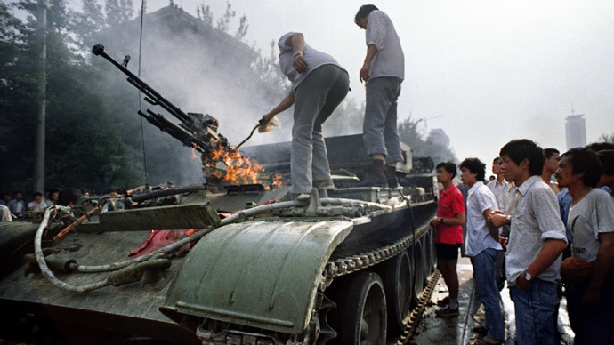 (FILES) In a file picture taken on June 4, 1989 Chinese residents check a burning armoured personnel carrier which was set on fire during clashes near Tiananmen Square in Beijing. (AFP Photo / Files / Tommy Cheng)