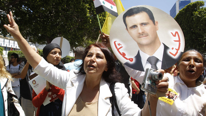 A woman together with others, including Syrians living in Tunisia, holds a placard of Syria's President Bashar al-Assad, in Tunis June 3, 2014. (Reuters)