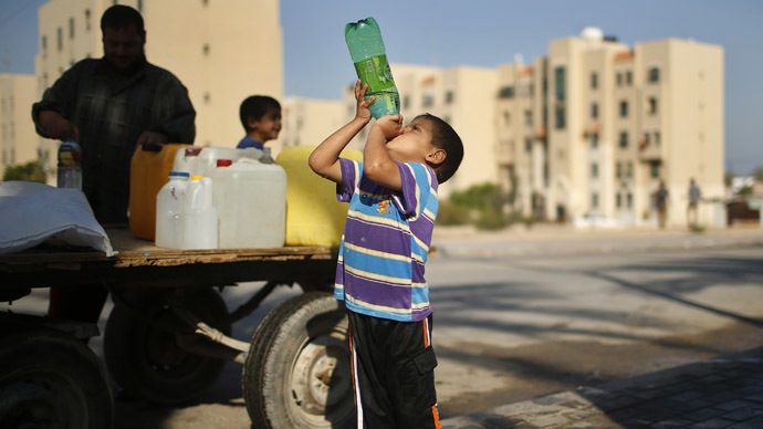 A Palestinian boy drinks water next to a cart loaded with containers filled with water from public taps in the northern Gaza Strip (Reuters/Mohammed Salem)