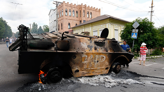 Residents look at a destroyed armoured personnel carrier of the DNR (Donetsk People's Reublic) at the site of fighting in the eastern Ukrainian port city of Mariupol June 13, 2014 (Reuters / Shamil Zhumatov)
