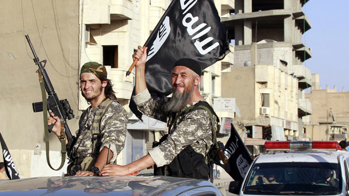 Militant Islamist fighters wave flags as they take part in a military parade along the streets of Syria's northern Raqqa province June 30, 2014. (Reuters)