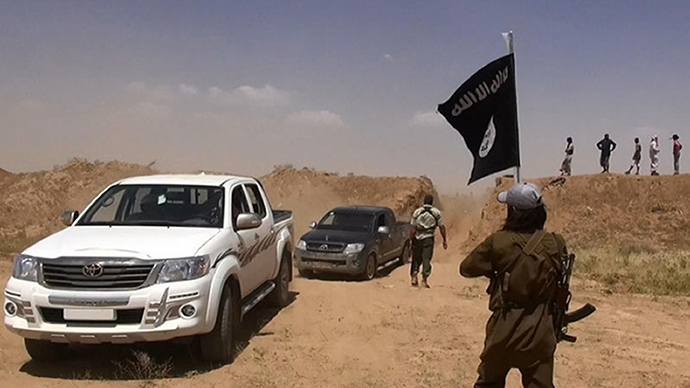A militant of the jihadist group Islamic State of Iraq and the Levant (ISIL) waving the Islamic Jihad flag as vehicles drive on a newly cut road through the Syrian-Iraqi border (AFP Photo / Albakara News)