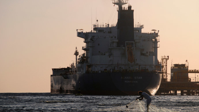 A fisherman pulls in his net as an oil tanker is seen at the port in the northwestern city of Duba.(Reuters / Mohamed Al Hwaity)