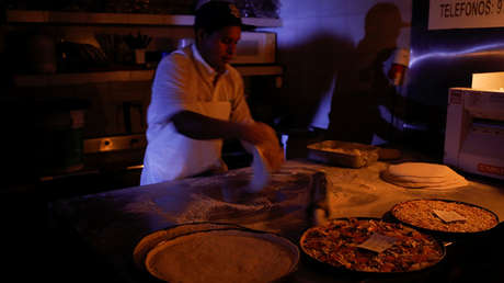 Un hombre cocina con velas y linternas en una pizzería durante un apagón en Caracas. 9 de marzo de 2019.