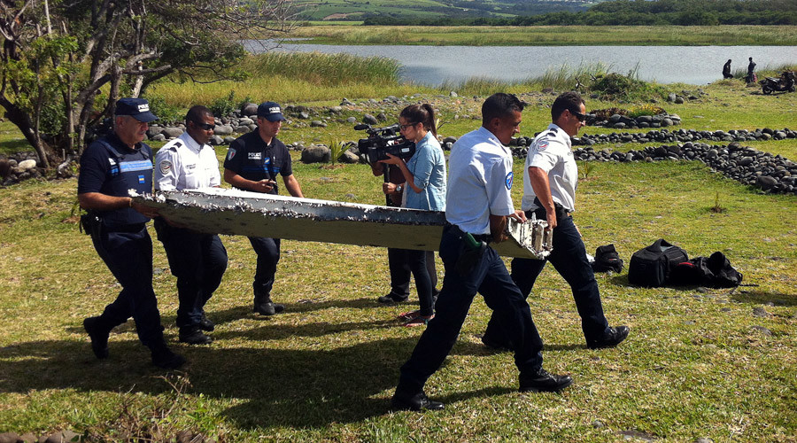 Police carry a piece of debris from an unidentified aircraft found in the coastal area of Saint-Andre de la Reunion, in the east of the French Indian Ocean island of La Reunion, on July 29, 2015. © Yannick Pitou