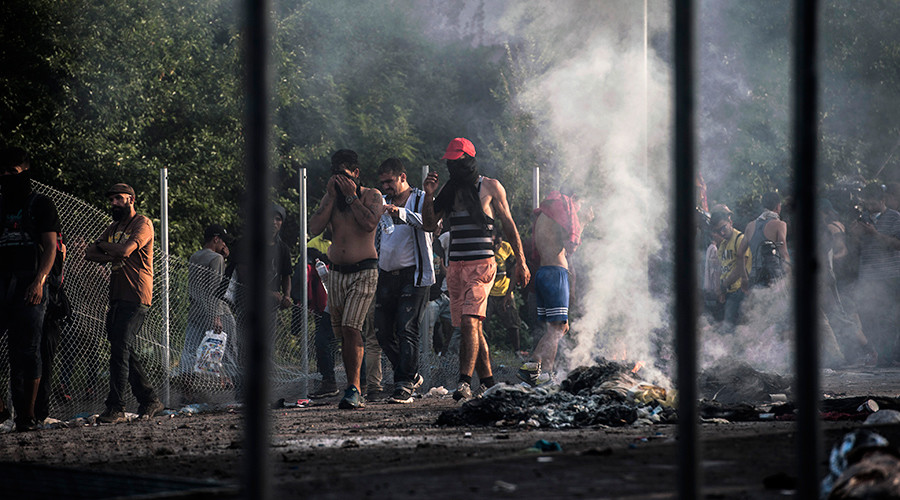 Refugees cover their faces from tear gas during clashes with Hungarian riot police at the Hungarian border with Serbia near the town of Horgos, on September 16, 2015 © Armend Nimani