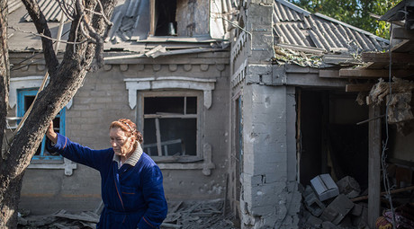 A woman stands by the house damaged during a mortar shelling in the village of Oleksandrivka, Donetsk Region. © Iliya Pitalev