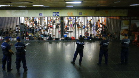 Hungarian police officers guard refugees at a makeshift camp in an underground station near the Keleti train station in Budapest, Hungary © Leonhard Foeger