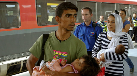 Migrants from Syria are accompanied by a Swiss police officer upon their arrival at the railway station in the north-eastern Swiss town of Buchs September 1, 2015. © Arnd Wiegmann
