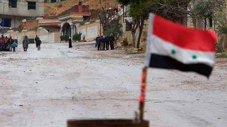 A Syrian national flag flutters near residents who said they have received permission from the Syrian government to leave the besieged town as they wait with their belongings after an aid convoy entered Madaya, Syria, January 14, 2016 © Omar Sanadiki