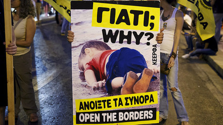 A man holds a placard with a photograph of three-year-old Syrian refugee boy Aylan Kurdi who died trying to reach Greece from Turkey, during a demonstration  in Athens, Greece, September 12, 2015. © Paul Hanna
