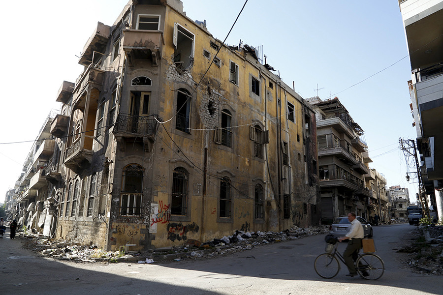 A man rides a bicycle near a building damaged during the Syrian conflict between government forces and rebels in Homs, Syria May 13, 2014 © Omar Sanadiki