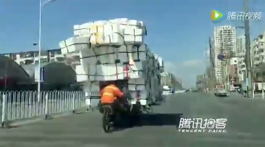 Chinese man defies gravity to transport mountain of boxes on tiny bike (VIDEO)