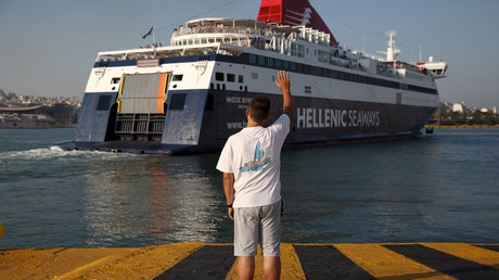 A man waves goodbye as a ship departs from the port of Piraeus, Greece © Yiannis Kourtoglou